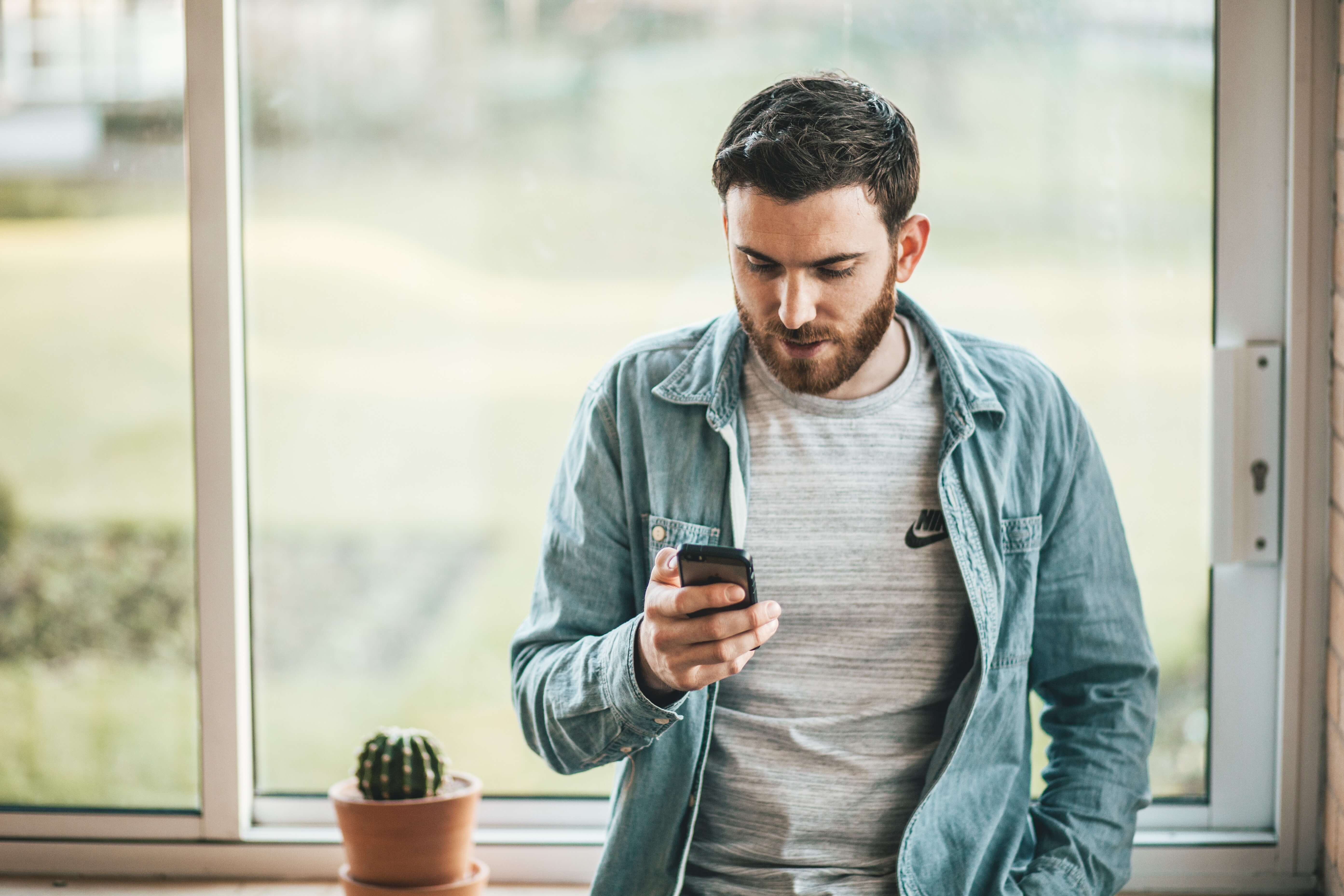 Young man looking at his phone in a light, airy room