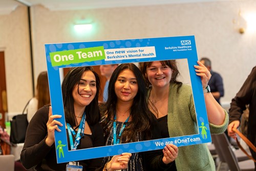 Attendees at the event posing with the One Team photo frame