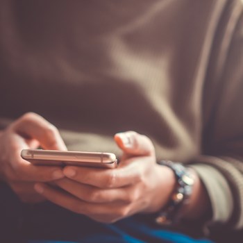 closeup of a person holding a phone in their hands, about to send a text message