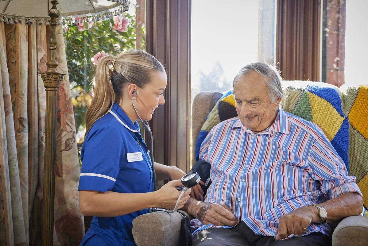Nurse with stethoscope checking Blood Pressure in Elderly Patient's Home