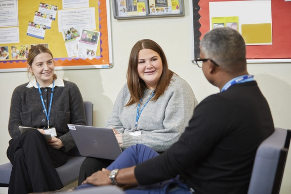 Three staff members, smiling in an office meeting