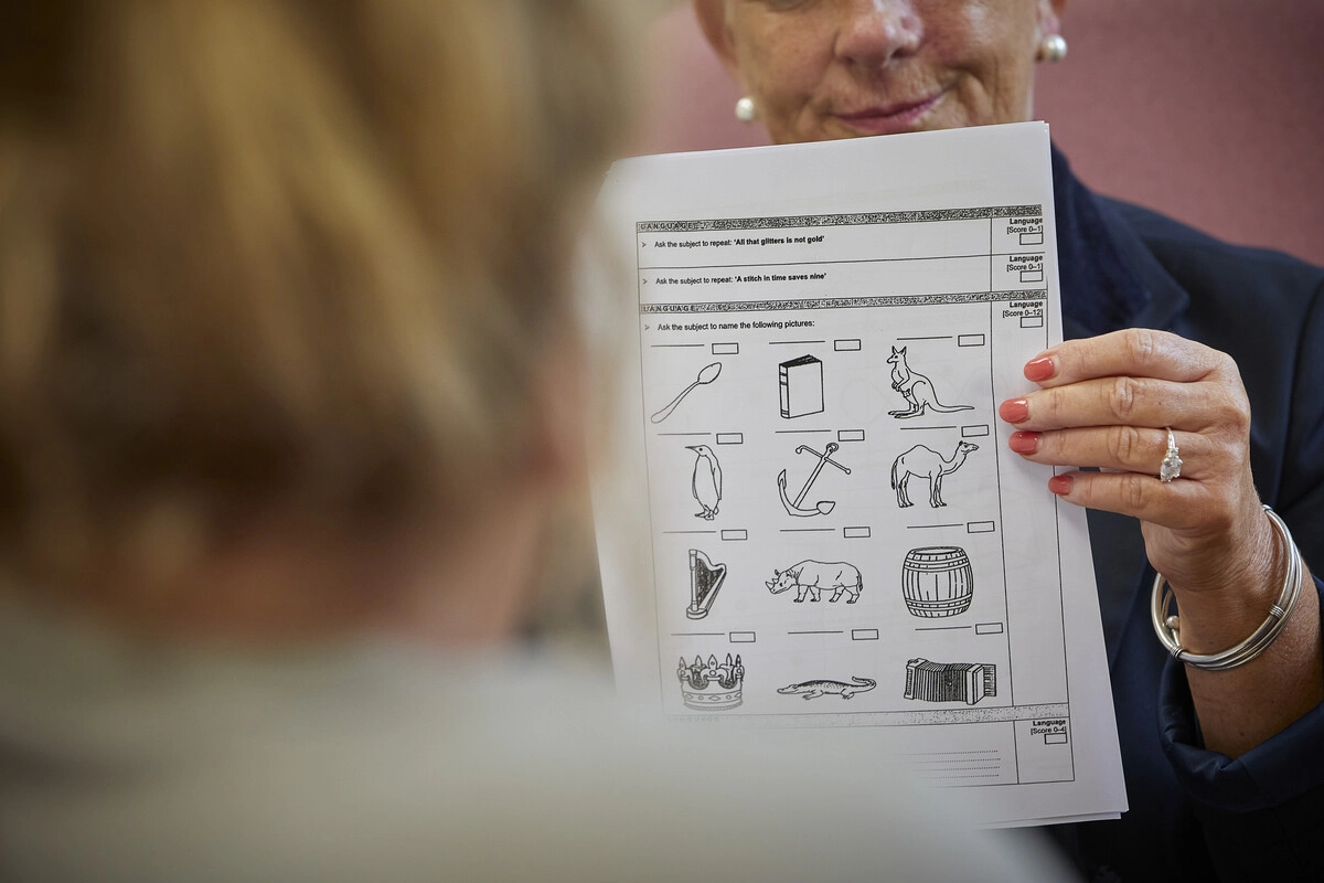 A closeup photo of a person holding up a test page of different pictures to a patient.