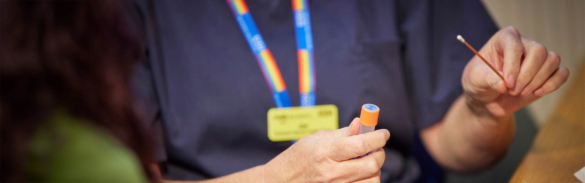 a closeup of a clinician showing a patient how to use a swab