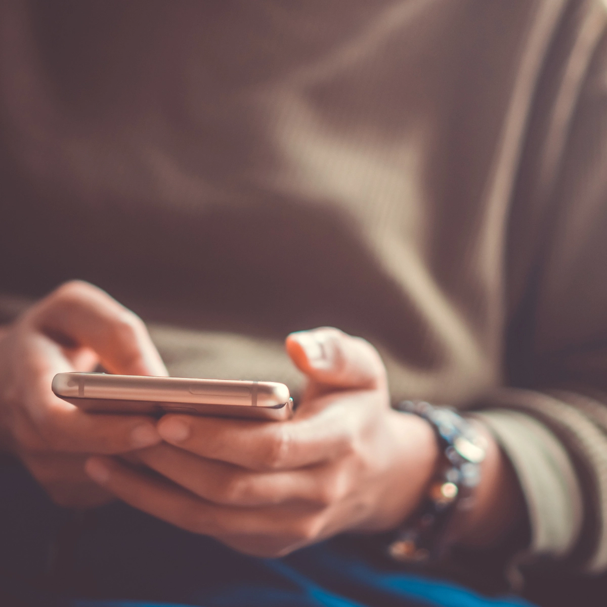 A closeup photo of a person's hands, using a smartphone