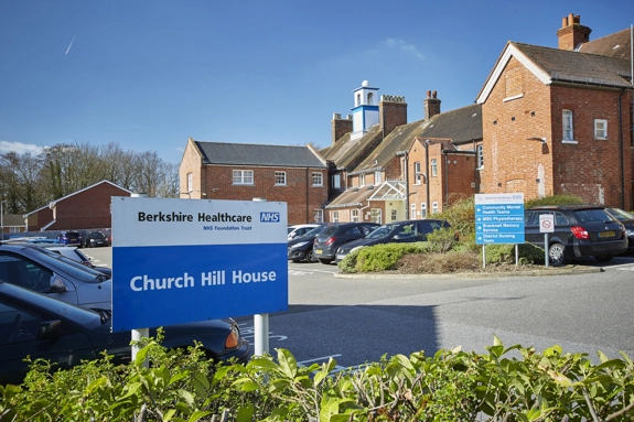 A sign that says "Church Hill House" in front of the car park, with the building in the background