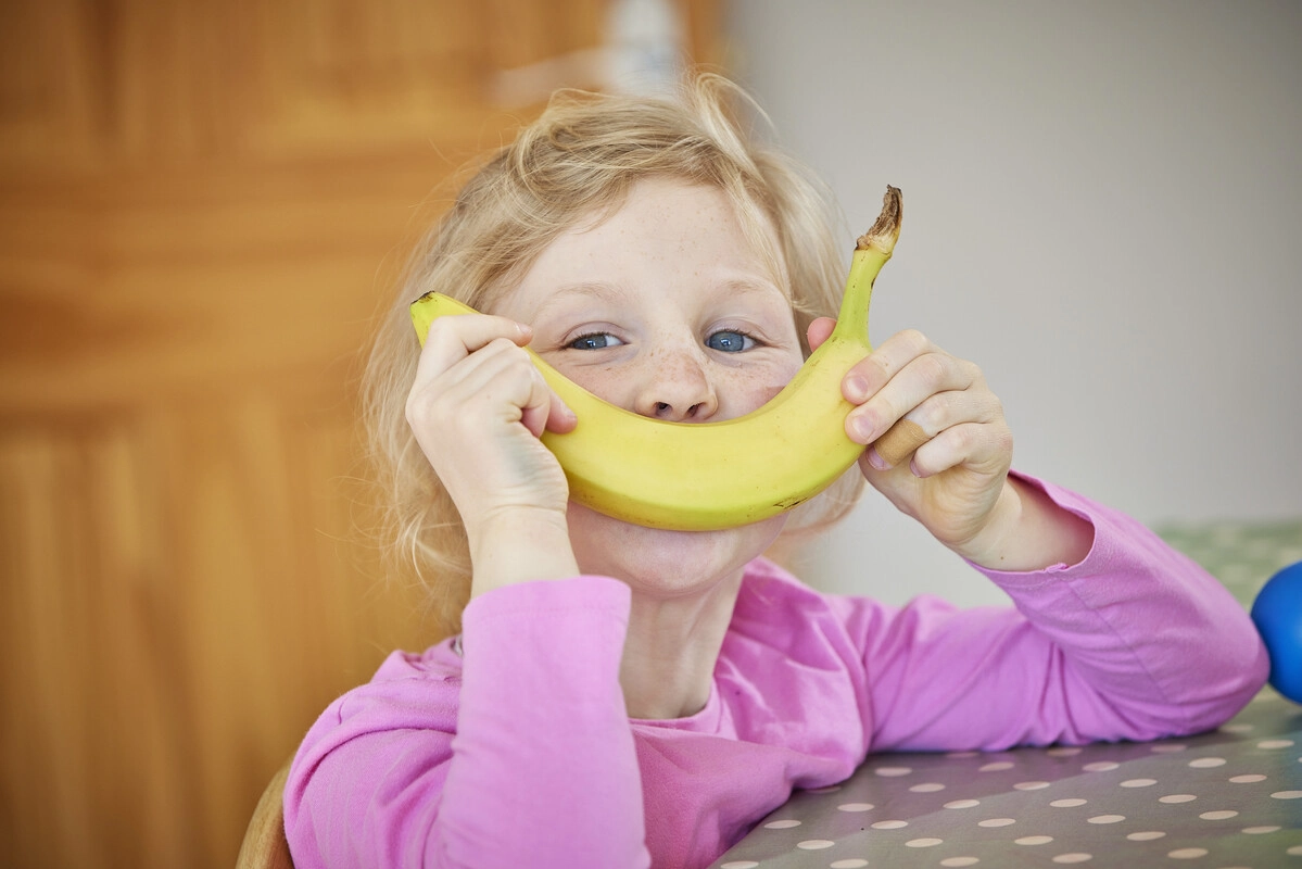 Girl holding a Banana up as a Smile