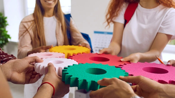 People holding together colourful cogs