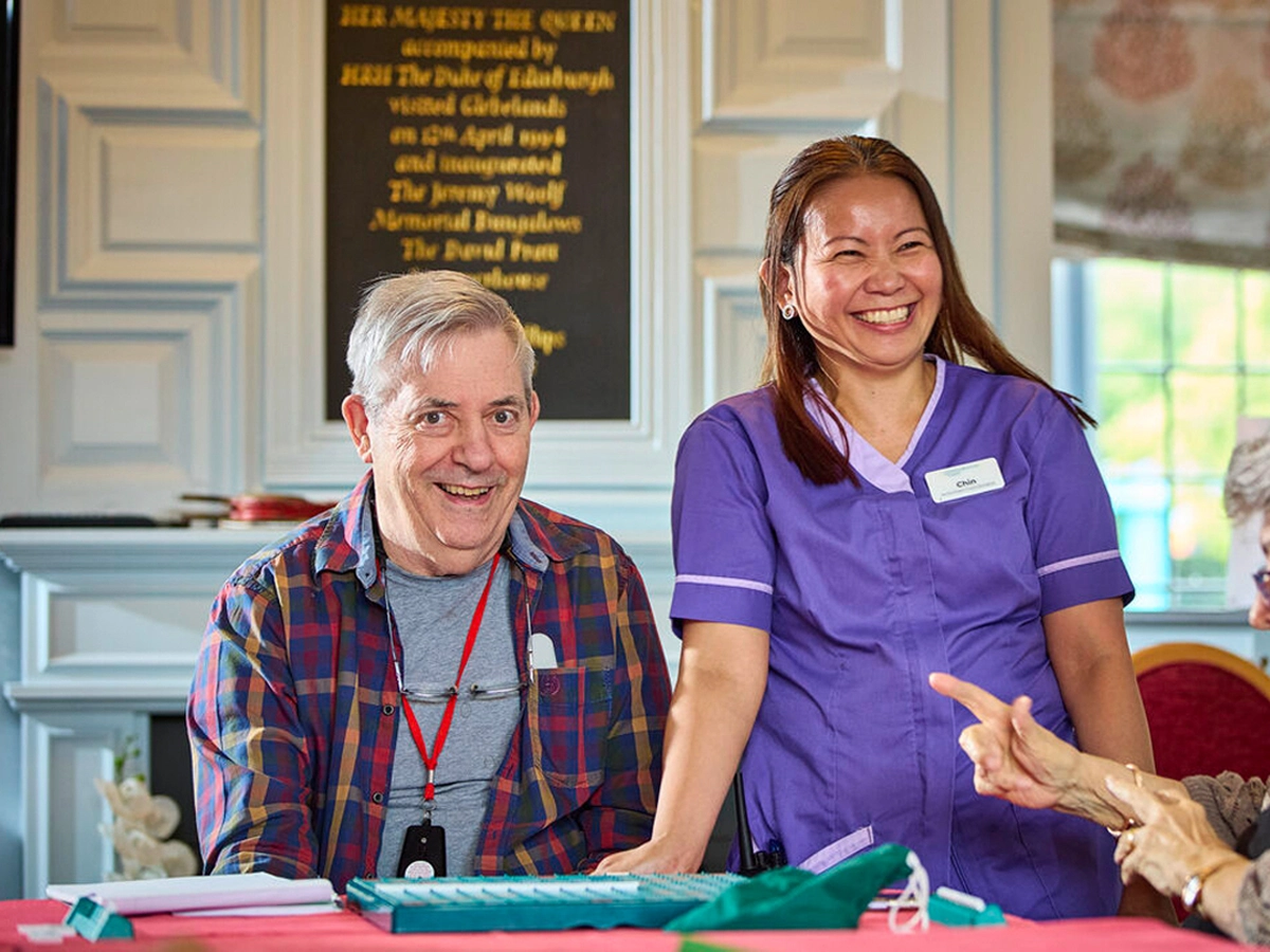 A care home resident and staff laughing together