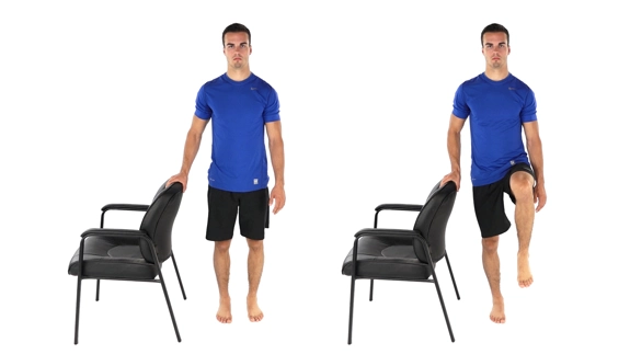 Person standing side-on by a chair with one hand on the back for support, and then raising the opposite knee.