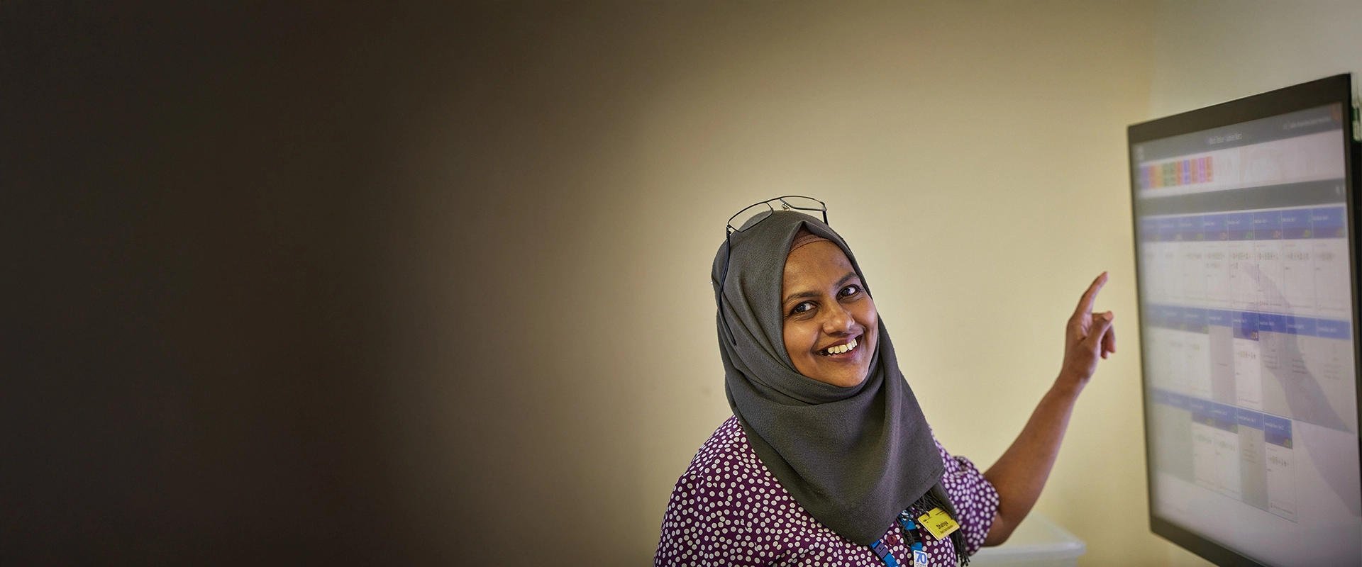 Staff smiling pointing at screen