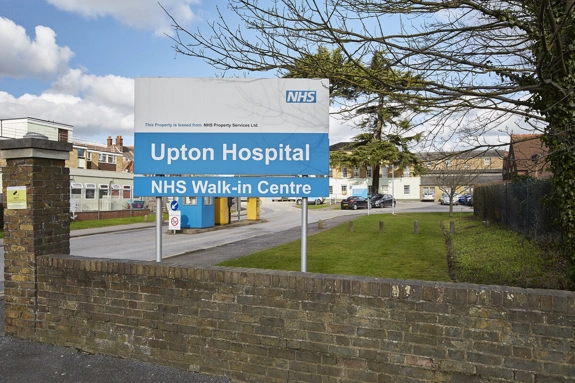 A sign that reads "Upton Hospital" and "NHS Walk-in Centre", at the entrance to the hospital