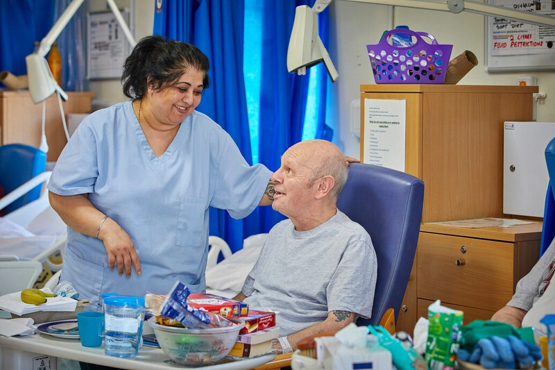 A nurse talking to a patient who is sitting in a chair