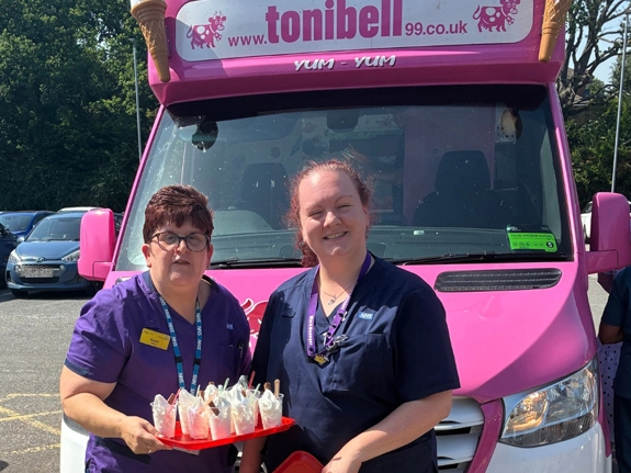 Two staff holding a tray of ice creams standing in front of a Tonibell ice cream van