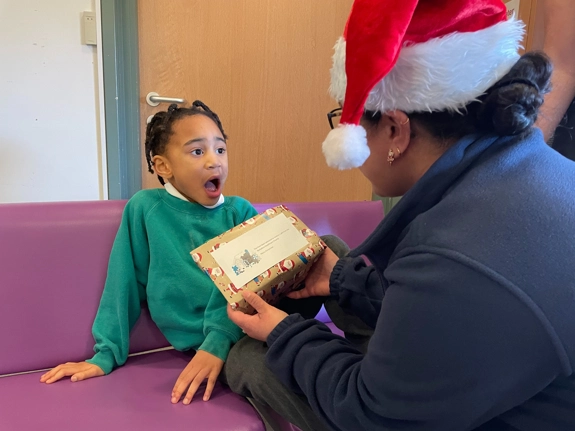 Child Receiving A Present from woman in santa hat