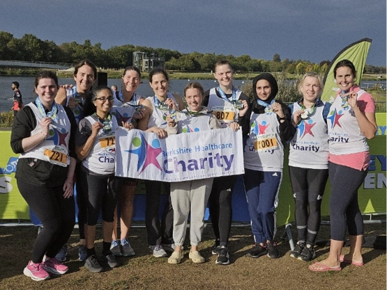 A group photo of 10 staff, holding their medals and the Berkshire Healthcare Charity banner