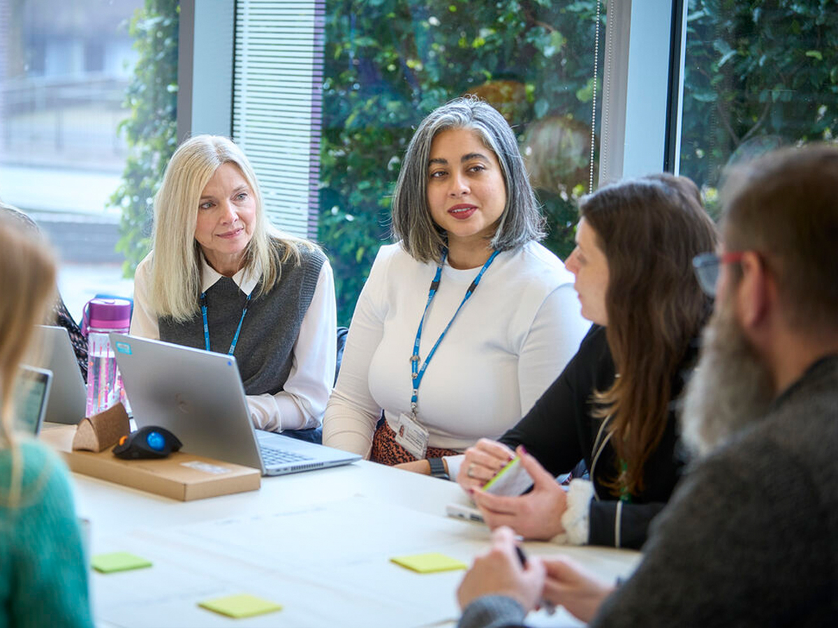 Group of staff at a meeting table with laptops and sticky notes