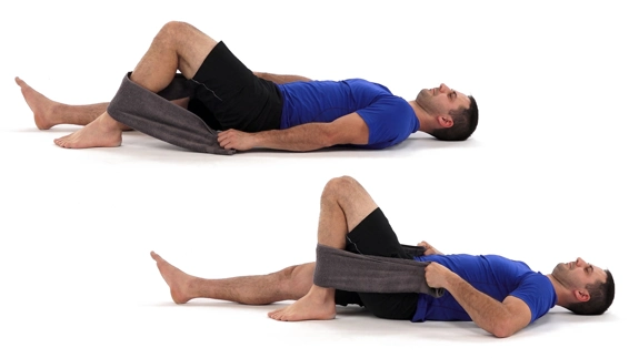 Person lying with one leg out straight and the other bent so foot flat on the floor. They have a towel hooked around the calf of the bent leg and are pulling at the ends.