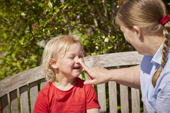 Parent putting sunscreen on boys nose