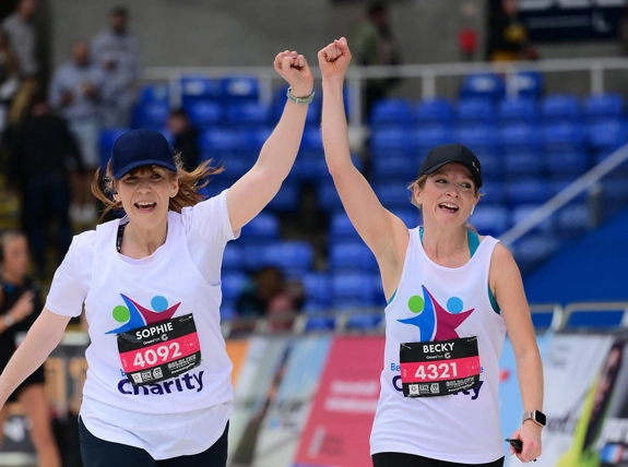 Two runners wearing Berkshire Healthcare Charity shirts with their fists raised high in celebration