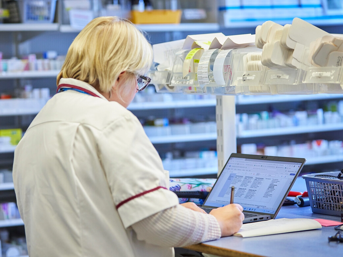 Pharmacy worker looking at a laptop in a pharmacy