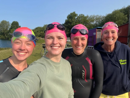 A selfie photo of four team members after swimming, wearing their swim caps