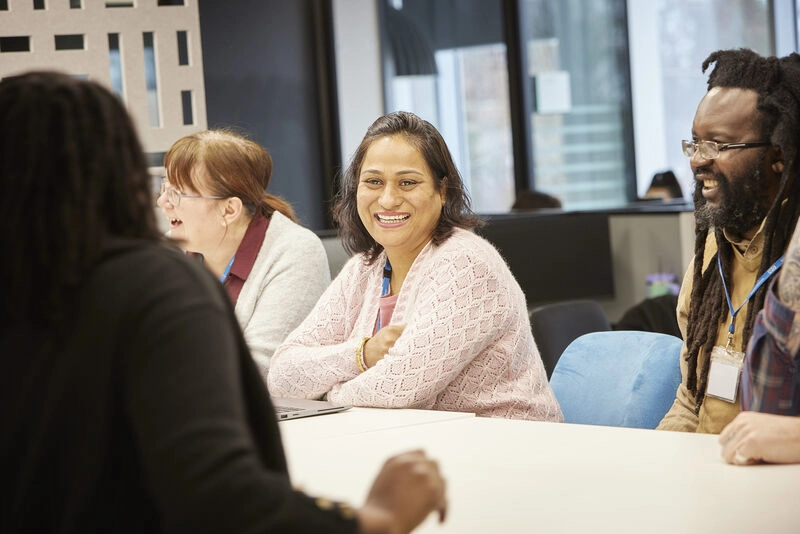 People Smiling At A Work Table