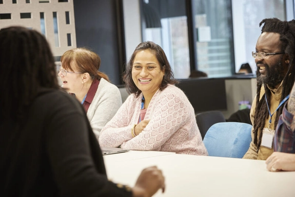 People Smiling At A Work Table
