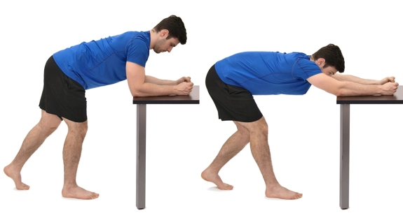 Person bent over table with forearms on the edge, and then shifting their weight back to straight arms.