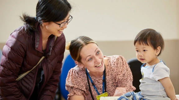 Staff member and guardian smiling at child