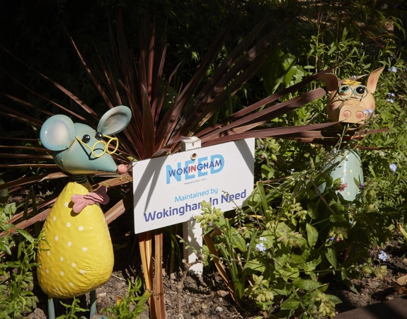 Sign reading "Maintained by Wokingham in Need" in flower bed