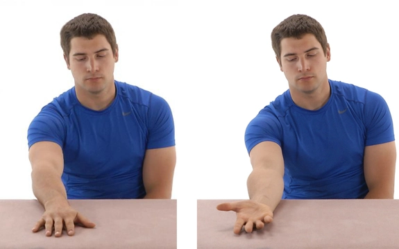 Person sat at a table with one arm by their side and the lower part of the other lying flat, palm down, and then palm up.