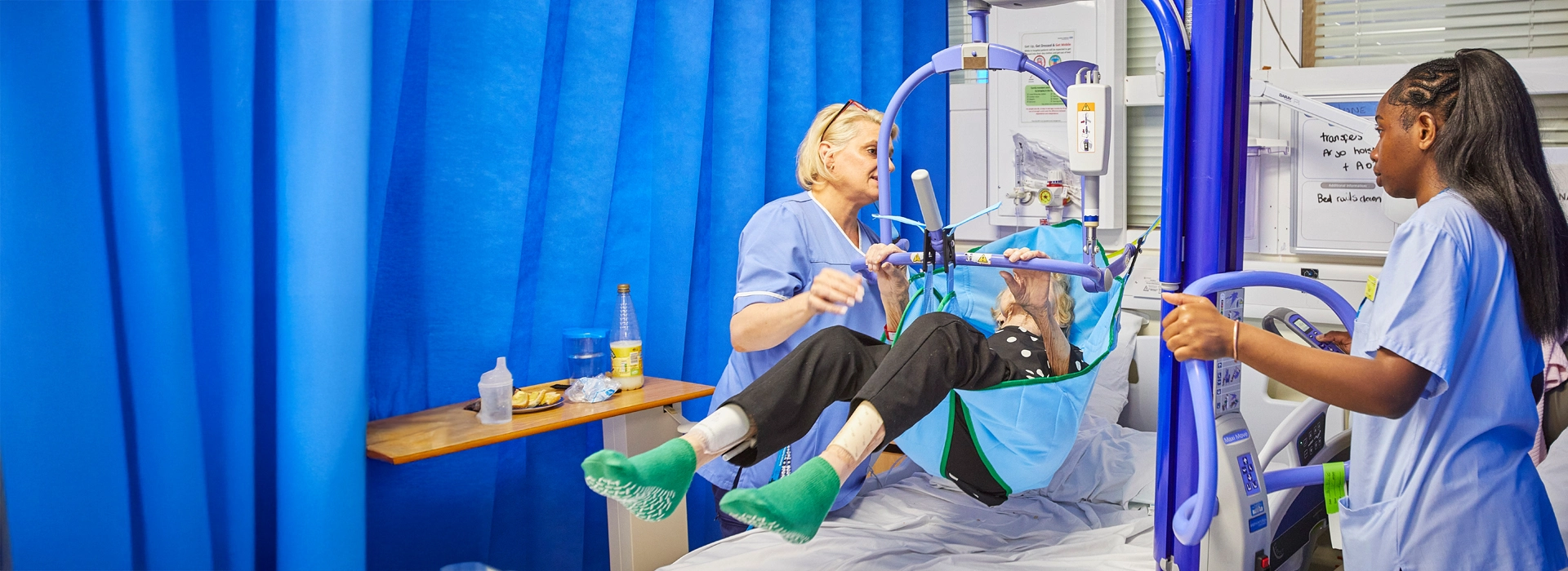 Healthcare assistants transferring a patient from bed