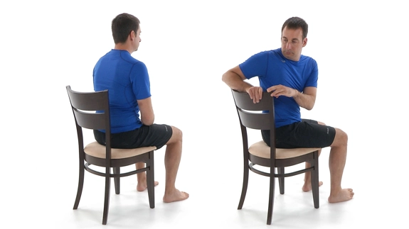 Person siting in chair with feet flat on the floor and twisting their upper half.