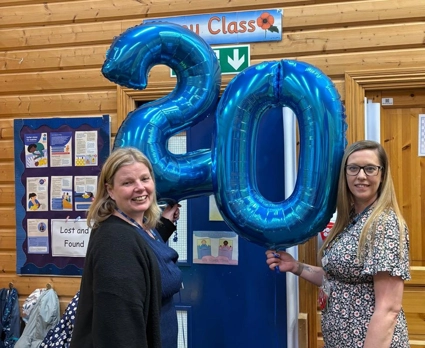 Staff holding balloons that say 20