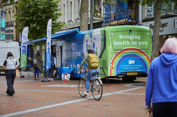 Bus with "Bringing health to you" written across it in a busy pedestrianised high street
