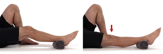 Person lying on with on leg bent so foot is flat on the floor, other leg is straight with ankle resting on rolled-up towel, going from slightly bent to straight.