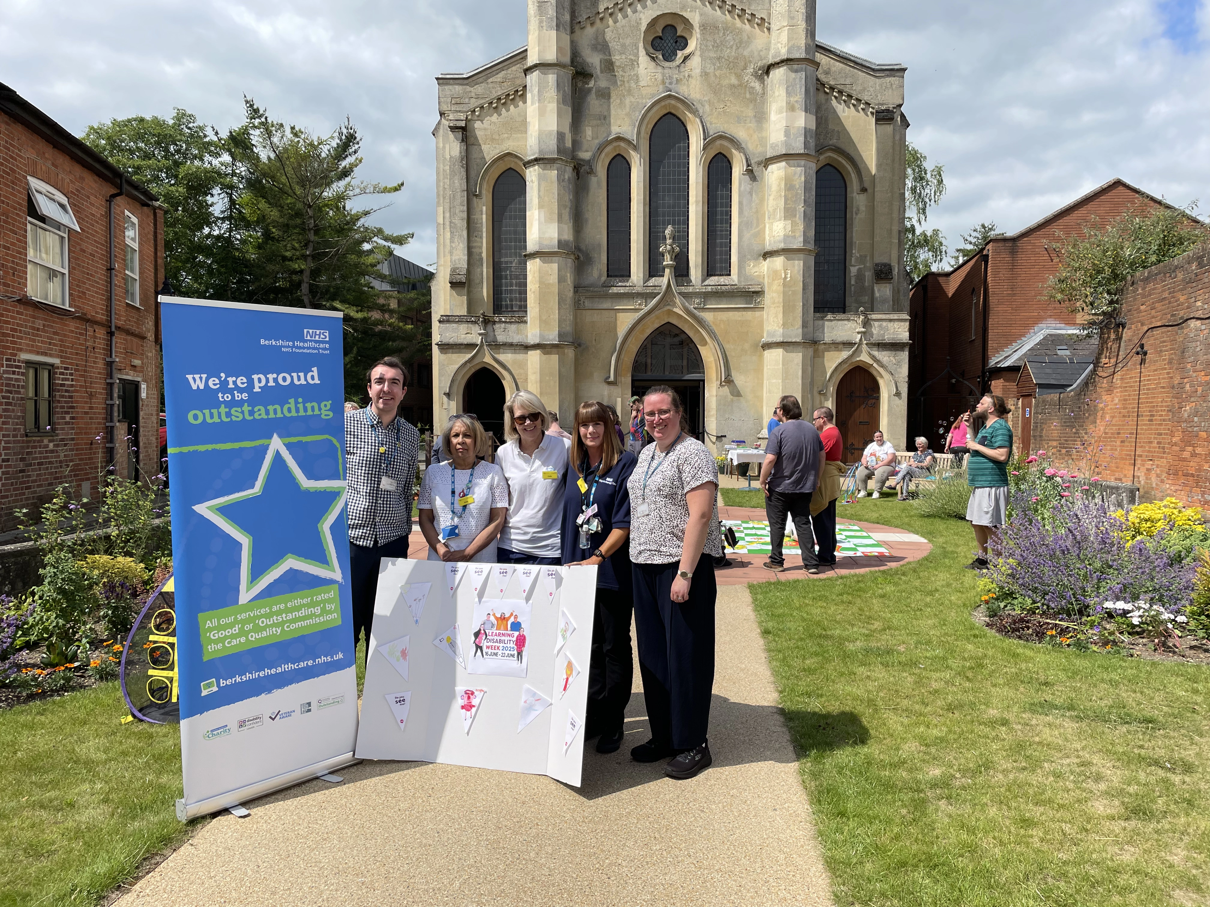 Five staff members from the LD service, standing outside near a display banner in the church grounds