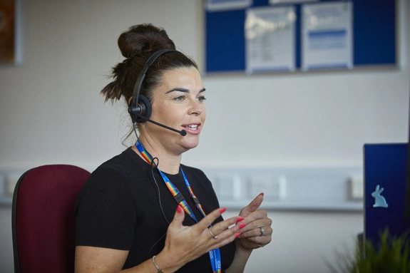 A staff member talking with a headset at a computer