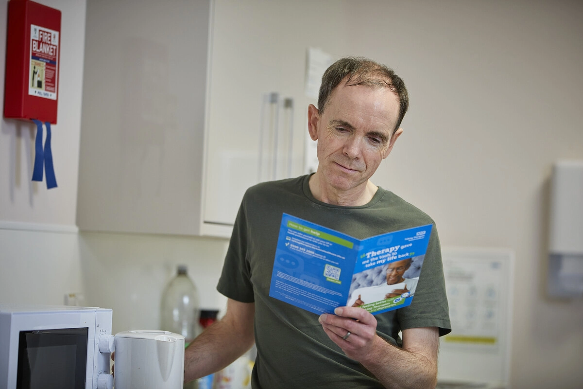 Man reading booklet in kitchen